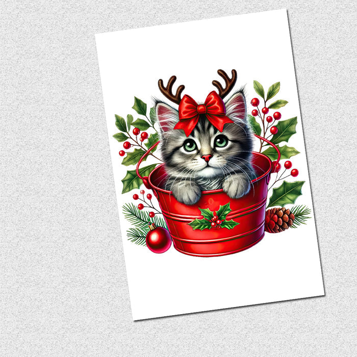 Illustration of a cat with reindeer antlers and a bow in a red bucket surrounded by Christmas decorations on a white background.