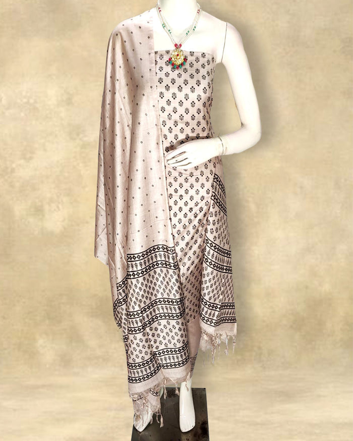 Light beige katan silk unstitched suit set with dark brown floral hand block print and horizontal panelled borders of repeating diamonds, dashes and dots.