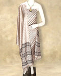 Light beige katan silk unstitched suit set with dark brown floral hand block print and horizontal panelled borders of repeating diamonds, dashes and dots.