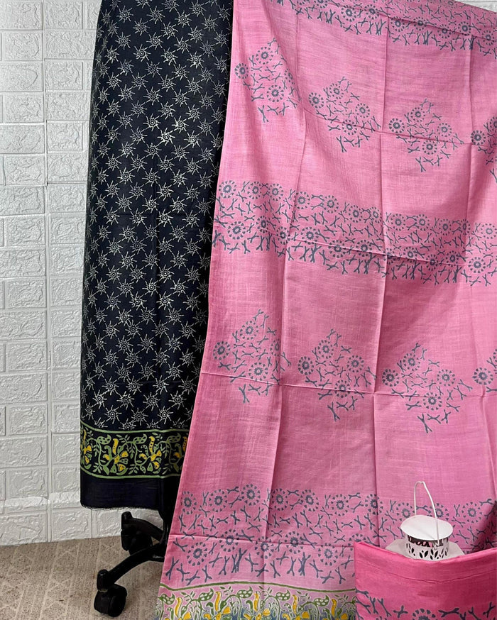 Black Katan silk suit set hand block printed with yellow and white geometric starburst motifs, paired with a contrast pink dupatta printed in floral clusters with banded edges.