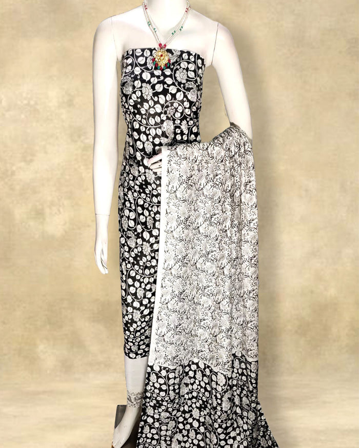 Black Katan silk unstitched suit set hand block printed with white floral and leafy vine motifs in a dense all-over repeat, shown with its contrast dupatta and distinct lower panel border.