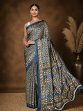 Dark blue and tan printed saree with geometric, leaf-like motifs and a dark blue border, styled with a reference blouse.