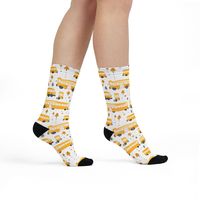 White socks with yellow school bus pattern worn by a person on a white background