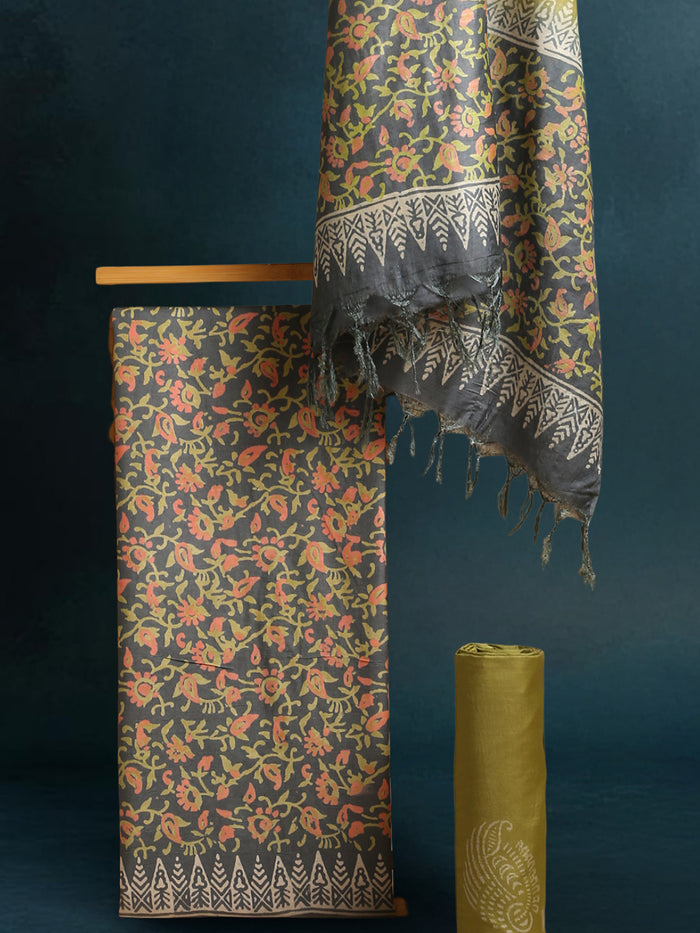 Charcoal grey and olive green Katan silk unstitched suit set with all-over floral paisley block print in muted earth tones, peach and pale yellow accents and a tasselled dupatta
