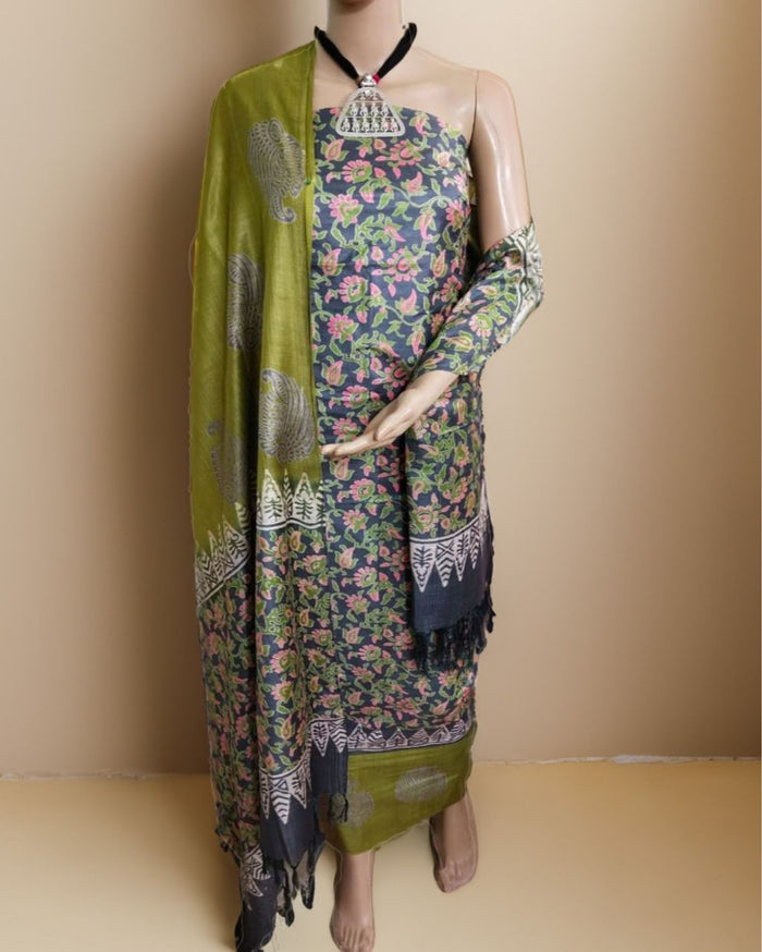 Charcoal grey and olive green Katan silk unstitched suit set with all-over floral paisley block print in muted earth tones, peach and pale yellow accents and a tasselled dupatta