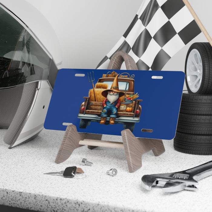 Blue license plate with a gnome and truck design on a stand, surrounded by tools and tires.