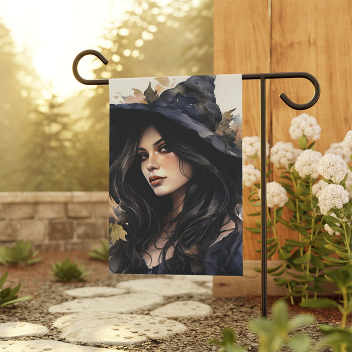 Decorative garden flag with a witch design hanging outdoors.