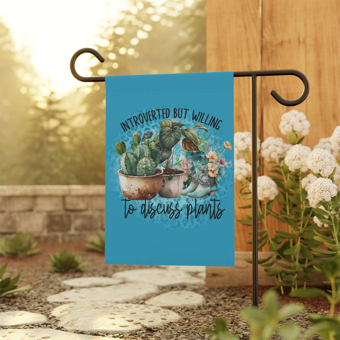 Garden flag with cacti design and text on a stand outdoors.