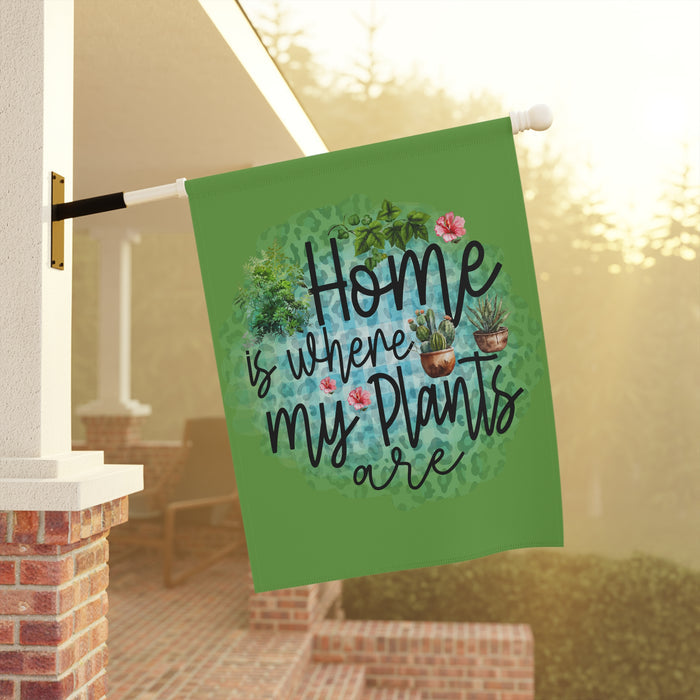 Decorative garden flag with 'Home is where my plants are' text and plant illustrations, hanging outdoors.