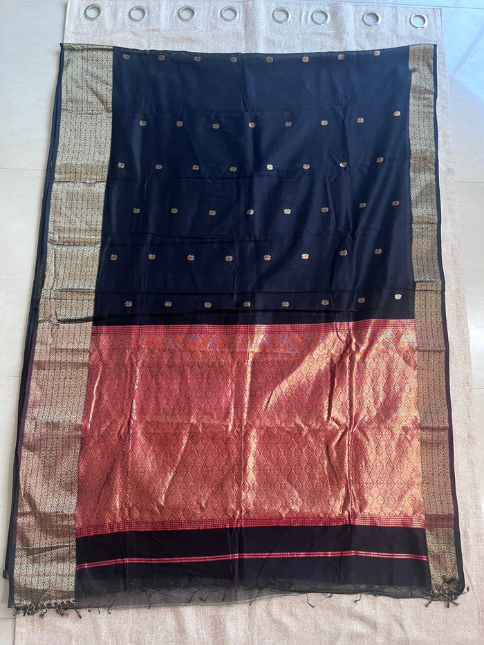 Matte black Maheshwari silk saree with small buti and wide copper-toned panelled borders, handwoven in Maheshwar