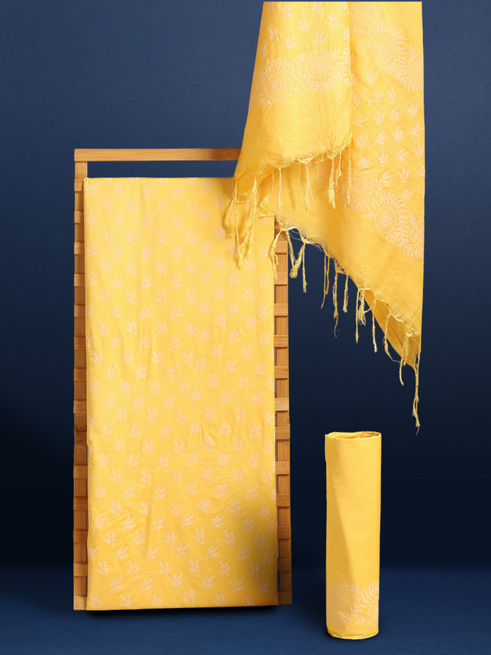 Golden yellow katan silk unstitched suit set with a small white leaf hand block print and a circular floral band with fringe on the dupatta