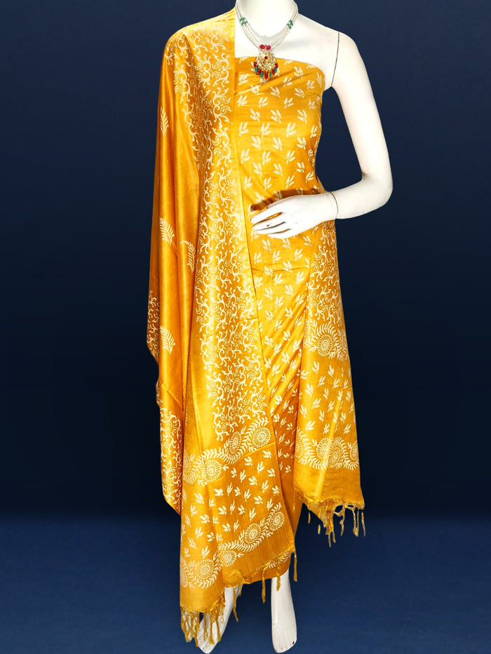 Golden yellow katan silk unstitched suit set with a small white leaf hand block print and a circular floral band with fringe on the dupatta