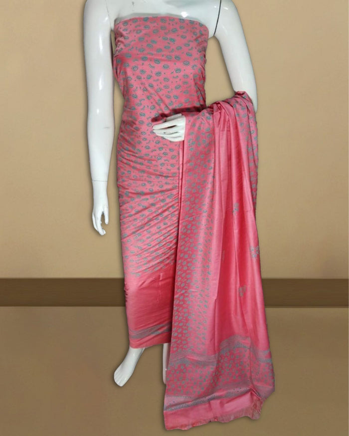 Bright pink katan silk unstitched suit set hand block printed with small grey floral motifs and a wide dark-grey patterned band at one end of the length.