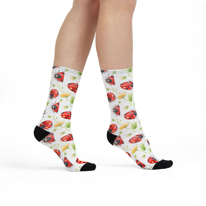 Socks with ladybug pattern worn by a person on a white background
