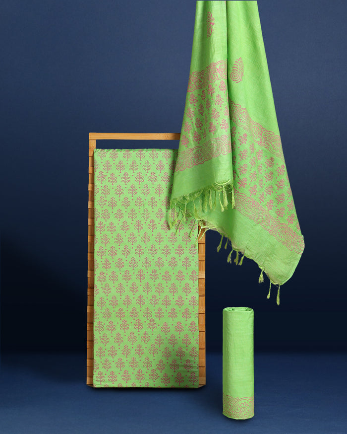 Lime green katan silk unstitched suit set hand block printed with terracotta botanical motifs, shown with a bordered dupatta finished in a short fringe.