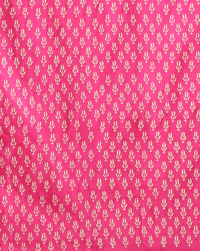 Magenta katan silk unstitched suit set hand block printed with small off-white sprigs, shown with a tasselled dupatta bordered in floral garlands and a plain bottom.