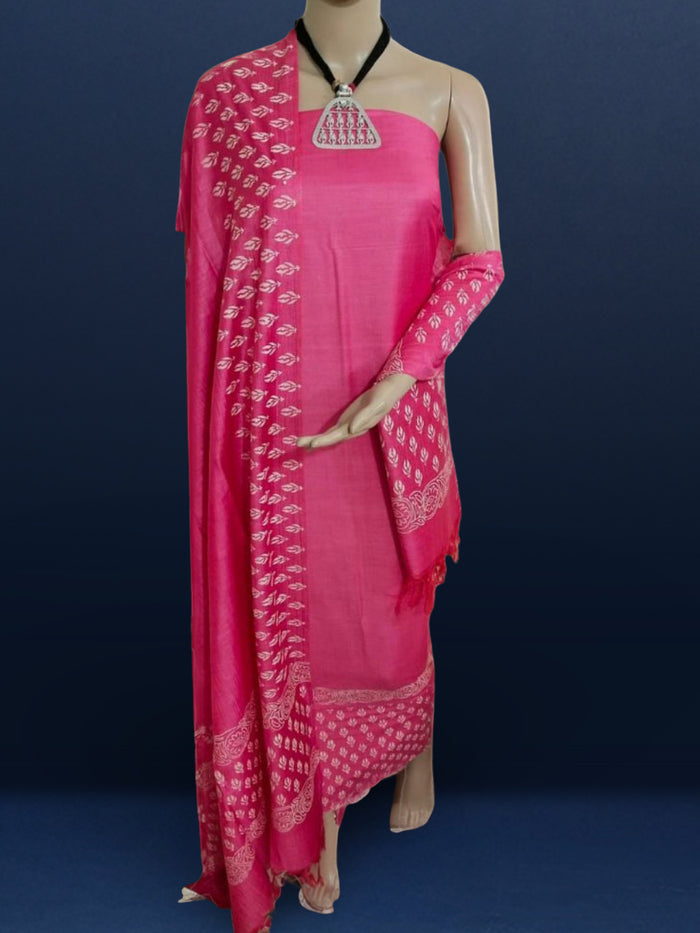 Magenta katan silk unstitched suit set hand block printed with small off-white sprigs, shown with a tasselled dupatta bordered in floral garlands and a plain bottom.