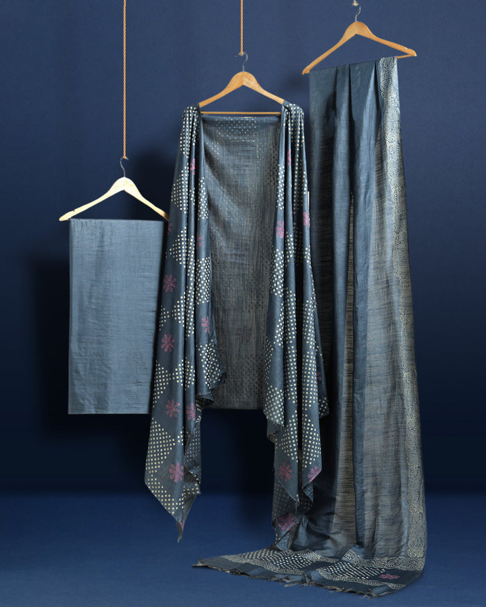 Deep metallic blue Katan silk suit set hand block printed with asymmetric sections of off-white polka dots and muted pink abstract florals, with a scrolling vine border on the dupatta.