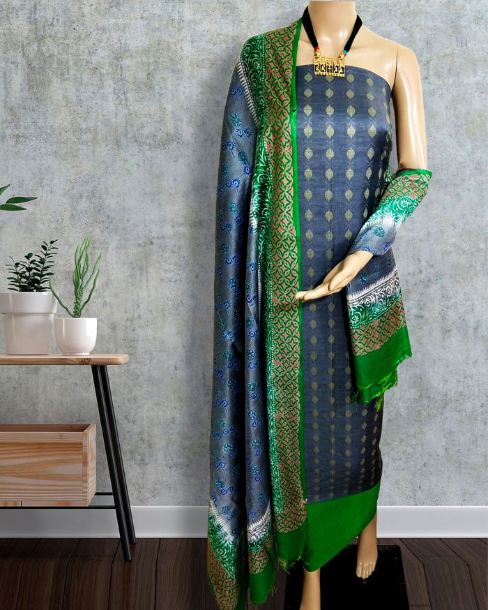 Navy blue katan silk unstitched suit set with a contrast bright green dupatta, colour blocked in wide bands with block-printed leaf geometry and circular medallions in gold and white.