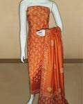 Warm orange katan silk unstitched suit set hand block printed with off-white botanical and geometric motifs, with a banded dupatta ending in plain orange silk.