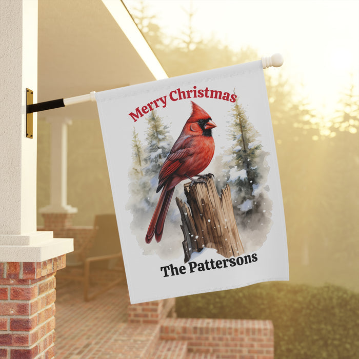 Christmas-themed garden flag with a cardinal and personalized text, hanging outdoors.