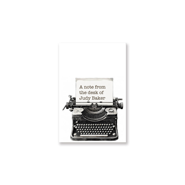 Vintage typewriter with 'A note from the desk of Judy Baker' text on a white background