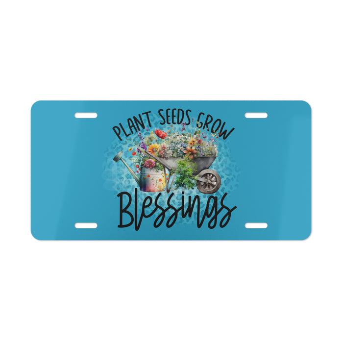 Blue license plate with garden-themed design and text 'Plant Seeds Grow Blessings' on a white background