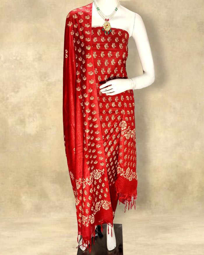 Red katan silk unstitched suit set with small all-over floral hand block print, and a dupatta with contrasting floral border and short fringe at the ends.