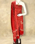 Red katan silk unstitched suit set with small all-over floral hand block print, and a dupatta with contrasting floral border and short fringe at the ends.