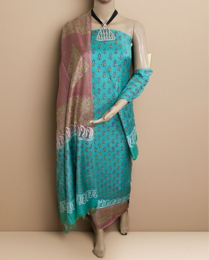 Sea green Katan silk unstitched suit set in saturated turquoise with gold-touched floral and paisley block print, contrasting mauve panels and geometric border bands