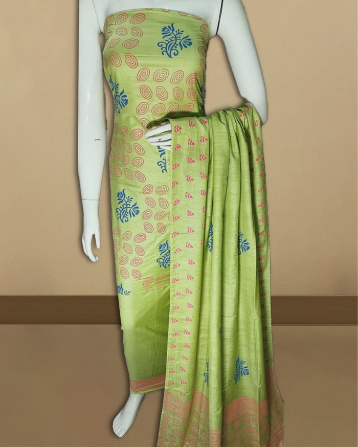 Soft green katan silk unstitched suit set with dense hand block printed swirl and floral motifs and a geometric hem band on the dupatta