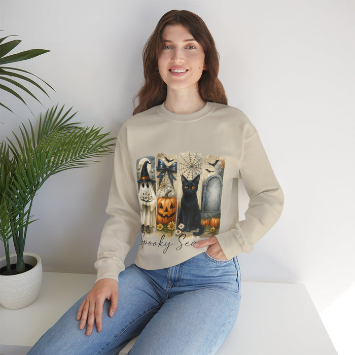 Woman wearing a beige sweatshirt with Halloween-themed design sitting on a white surface.