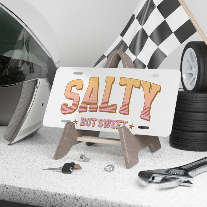 License plate with 'Salty But Sweet' text on a stand with car accessories in the background