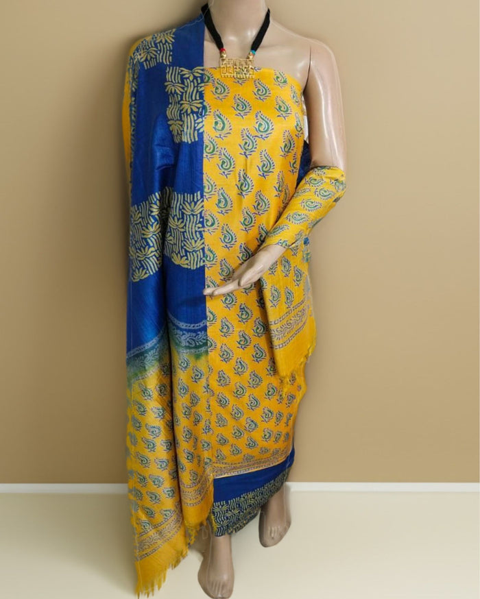 Yellow and blue colour-blocked Katan silk unstitched suit set with small paisley and abstract botanical block prints, green accents and patterned bands at the hem and edges